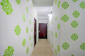 Un pasillo con papel tapiz estampado y una puerta al final.