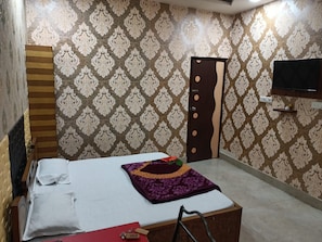 Una camera con un letto, un armadio, una televisione a parete e carta da parati decorata.