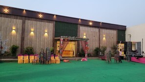 A venue with a stage, chairs, and a green carpeted area. - Hotel O Hindustan Villa (Asansol)