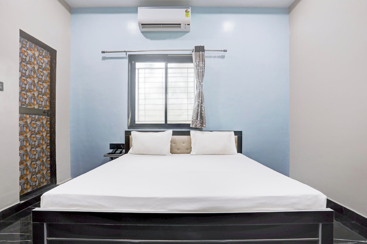 Ein Hotelzimmer mit einem Bett, einem Telefon, einer Klimaanlage und einem Vorhangfenster.