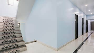 A modern interior with a staircase featuring geometric patterns, light blue walls, and a clean, polished floor.
