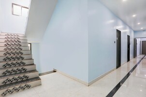 Un interior moderno con una escalera que presenta patrones geométricos, paredes azul claro y un suelo pulido y despejado.