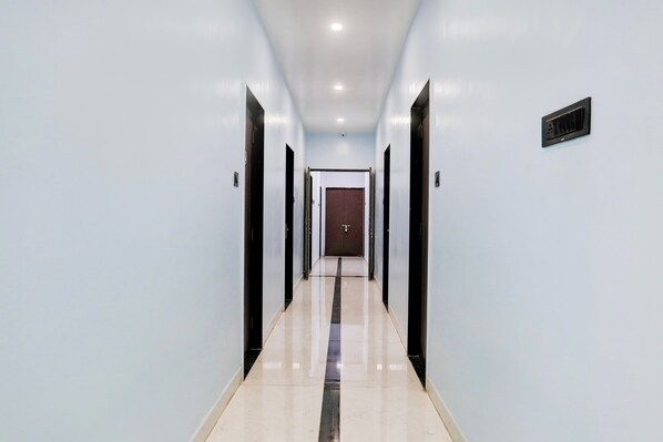 A corridor with doors on both sides, a tiled floor, and a ceiling with recessed lighting. - Hotel O by OYO Raj Guest House (Akola)