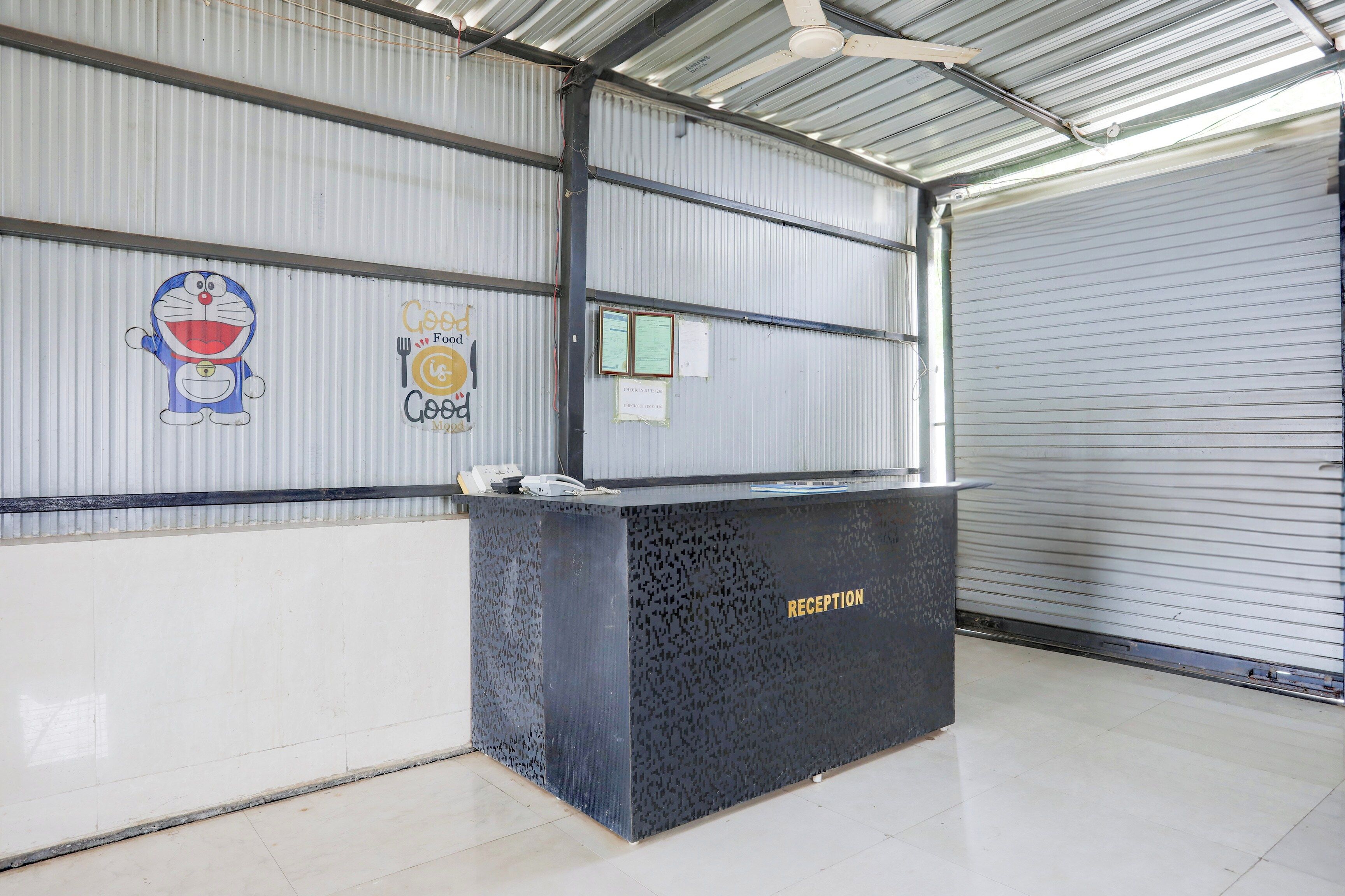 Un mostrador de recepción en un edificio de estilo almacén, con paredes de metal corrugado y una puerta enrollable cerrada.