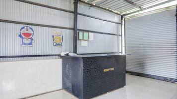 Un mostrador de recepción en un edificio de estilo almacén, con paredes de metal corrugado y una puerta enrollable cerrada.