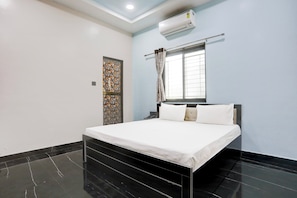 A hotel room with a bed, a window with curtains, an air conditioning unit, and a decorative door. - Hotel O by OYO Raj Guest House (Akola)