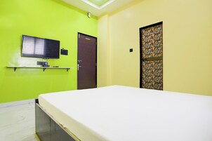 Una habitación con una cama, un televisor montado en la pared y una puerta con un diseño decorativo.