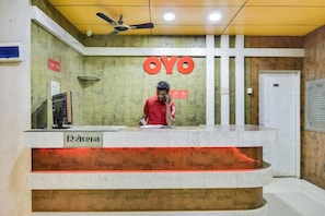 Una mesa de recepción con un cartel que dice 'OYO' y un hombre de pie detrás.