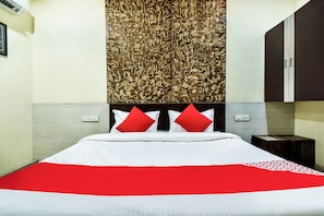 Una habitación de hotel con cama, aire acondicionado de pared, mesita de noche y armario.