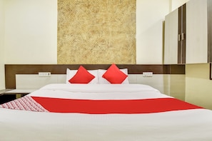 Habitación de hotel con cama, mesita de noche, espejo y pared con textura.