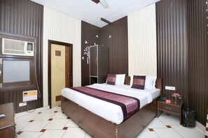 Habitación de hotel con una cama grande, una mesita de noche y un equipo de aire acondicionado instalado en la pared, además de una puerta.