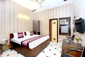 A hotel room with a bed, bedside table, desk, chair, TV, and a wardrobe. - Hotel O H.K.Continental (Amritsar)