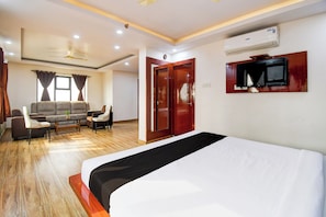 A hotel room with a bed, a sofa, a TV, and a ceiling fan.