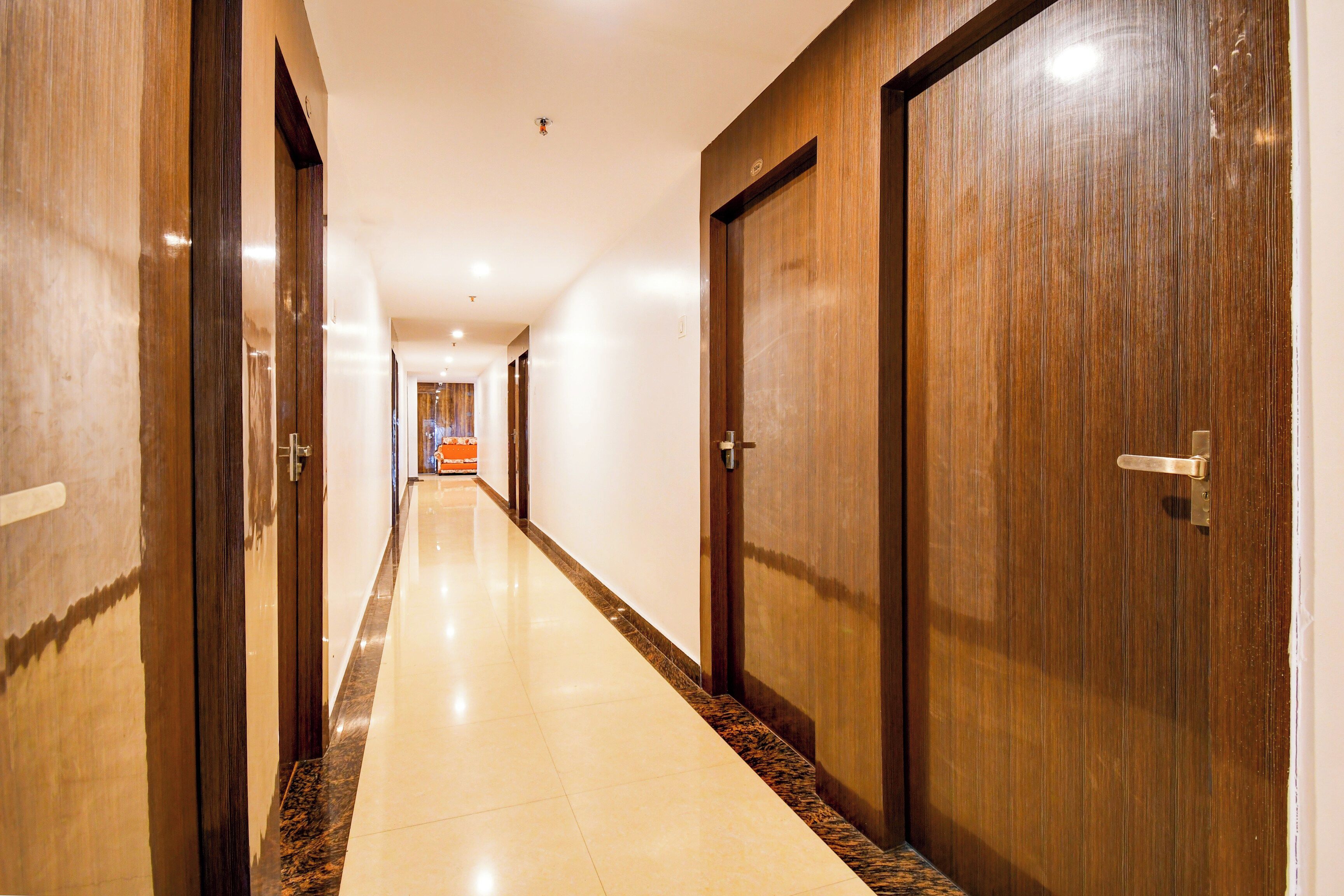 A hotel corridor with wooden doors and a tiled floor.