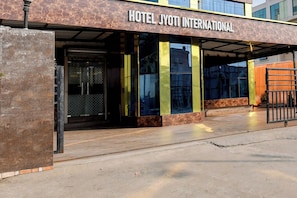 Das Hotel Jyoti International zeigt sich von außen mit einem modernen Design, einschließlich einer markanten Eingangspforte und einem überdachten Bereich mit Glasüren.