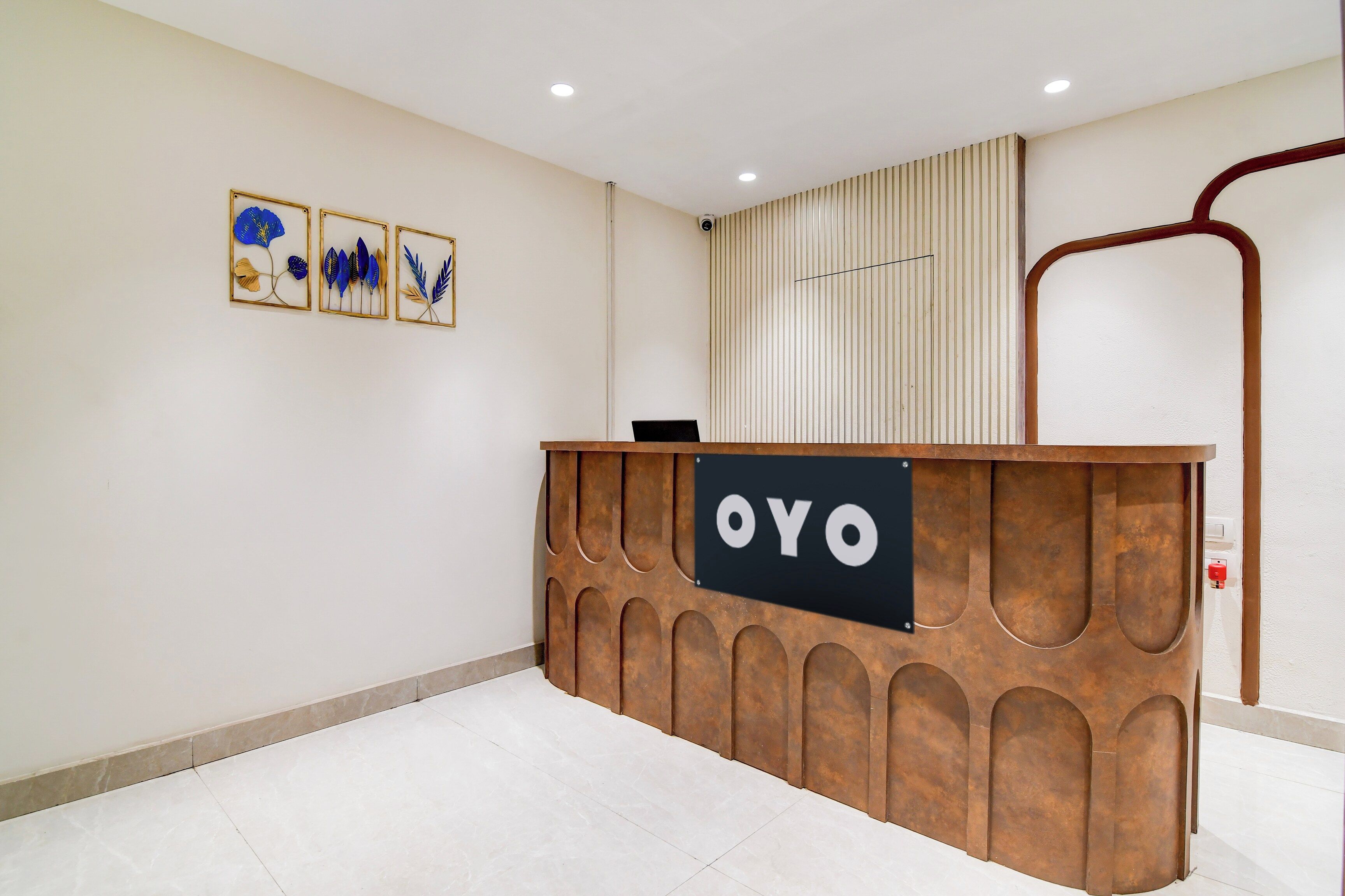 Uma receção com uma placa a indicar 'OYO', num interior moderno com soalho em mosaico e decoração na parede.