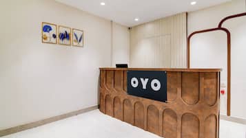 Uma receção com uma placa a indicar 'OYO', num interior moderno com soalho em mosaico e decoração na parede.