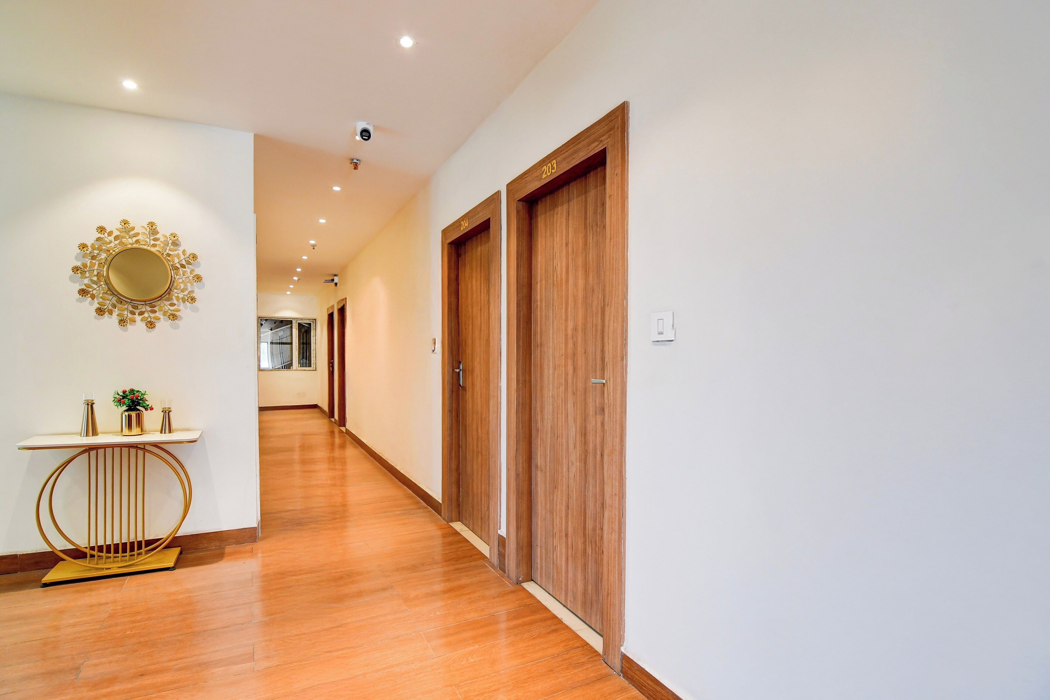 A hallway with wooden flooring, a white wall, and a wooden door with the number 204.