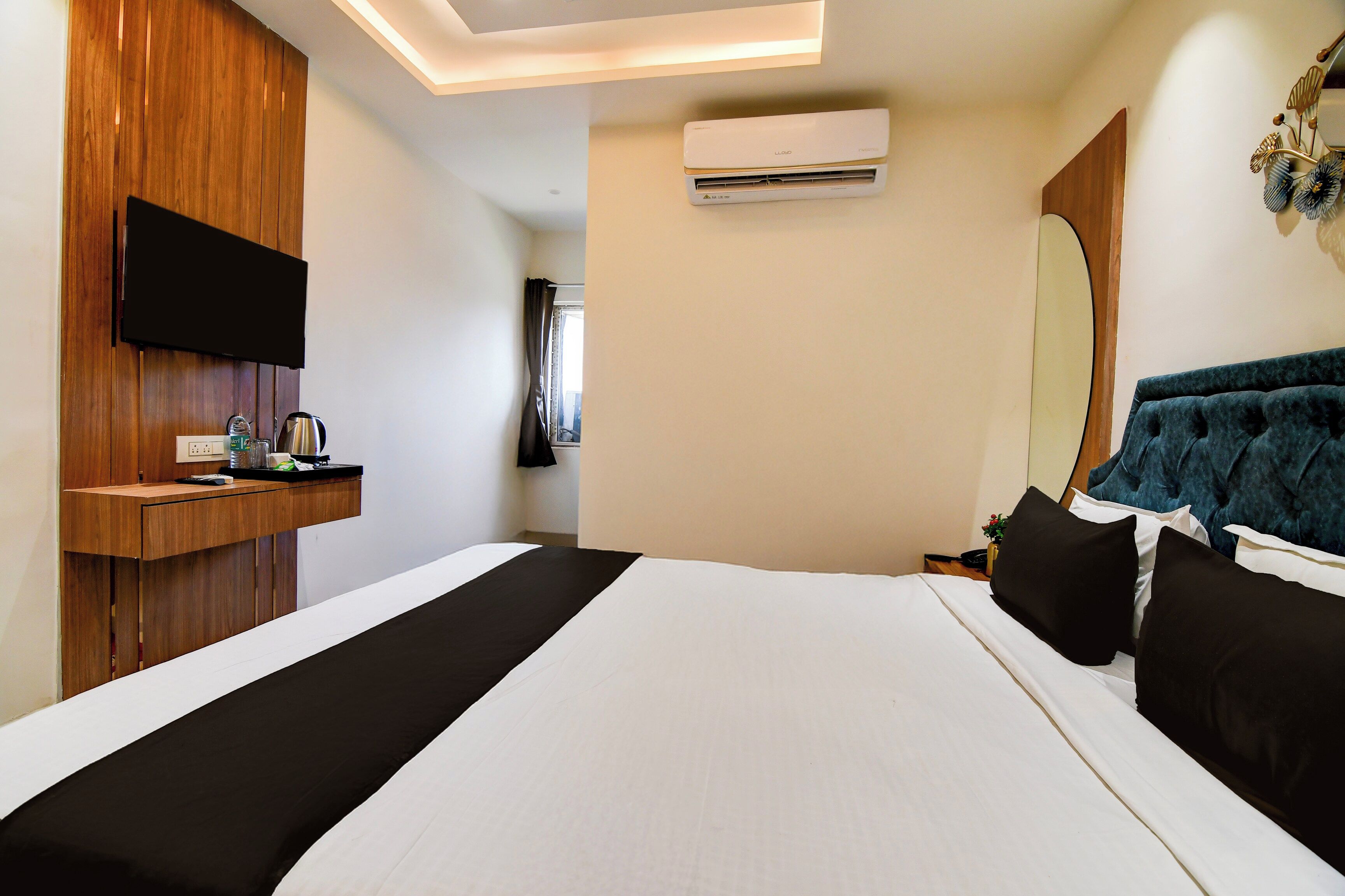 Quarto de hotel com cama, escrivaninha, TV de tela plana, ar condicionado e espelho.