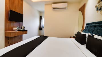 Quarto de hotel com cama, escrivaninha, TV de tela plana, ar condicionado e espelho.