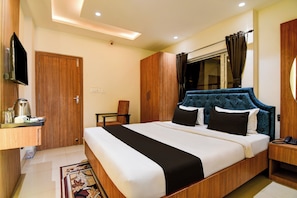 Camera d'albergo con un letto grande, un armadio in legno, un tavolino con un bollitore e un televisore montato a parete.