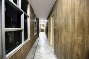 A corridor with wooden paneling on both sides, leading to a set of doors at the end. - Hotel O Sallow International (Amritsar)