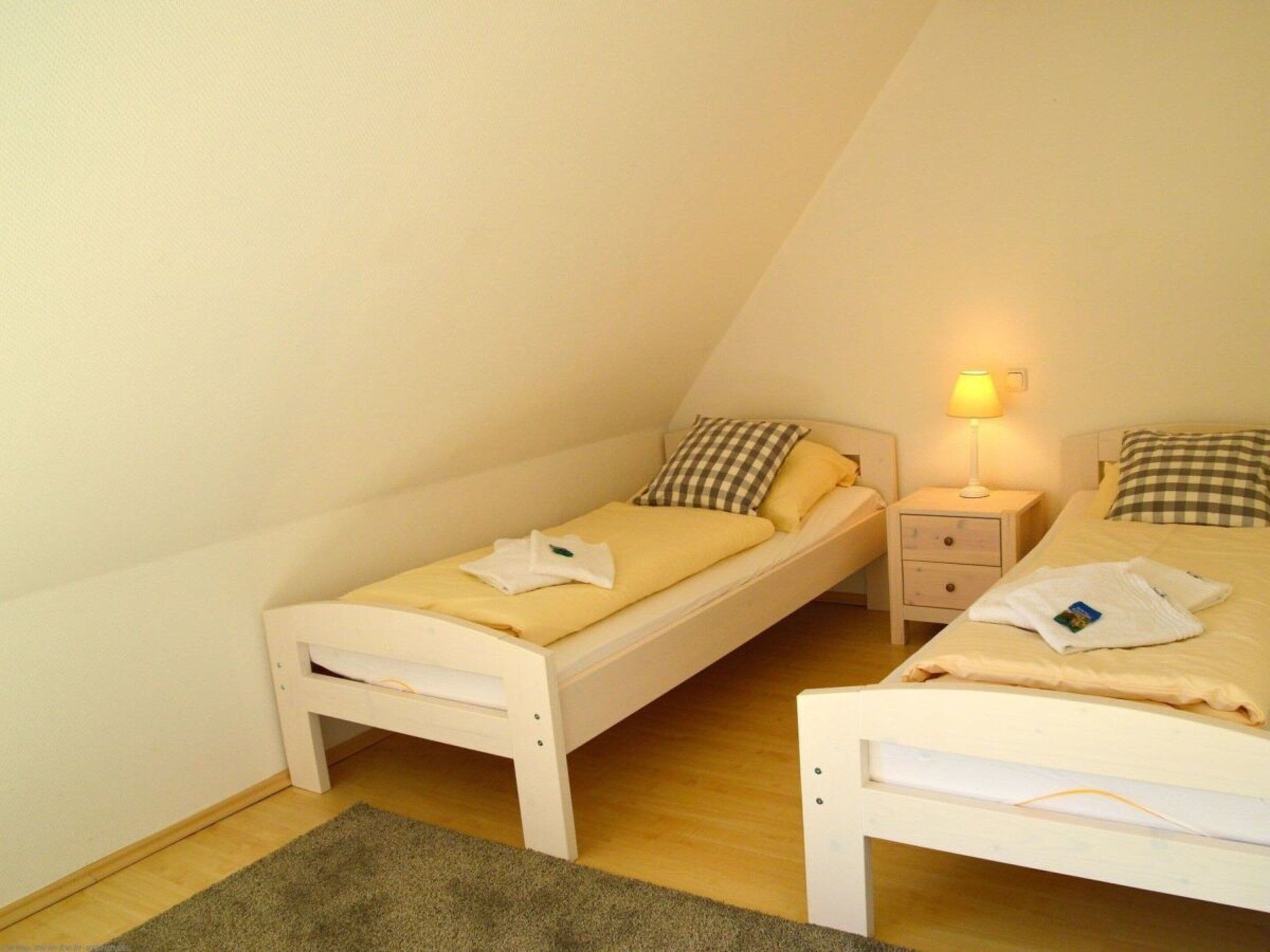 Un petit logement composé d’une seule pièce, comprenant deux lits, une table de chevet et une lampe.