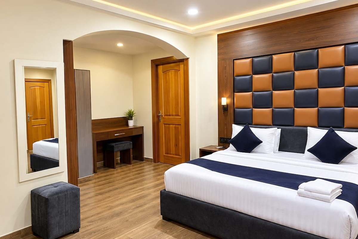 Una habitación de hotel con una cama grande, un escritorio, una silla y un espejo.