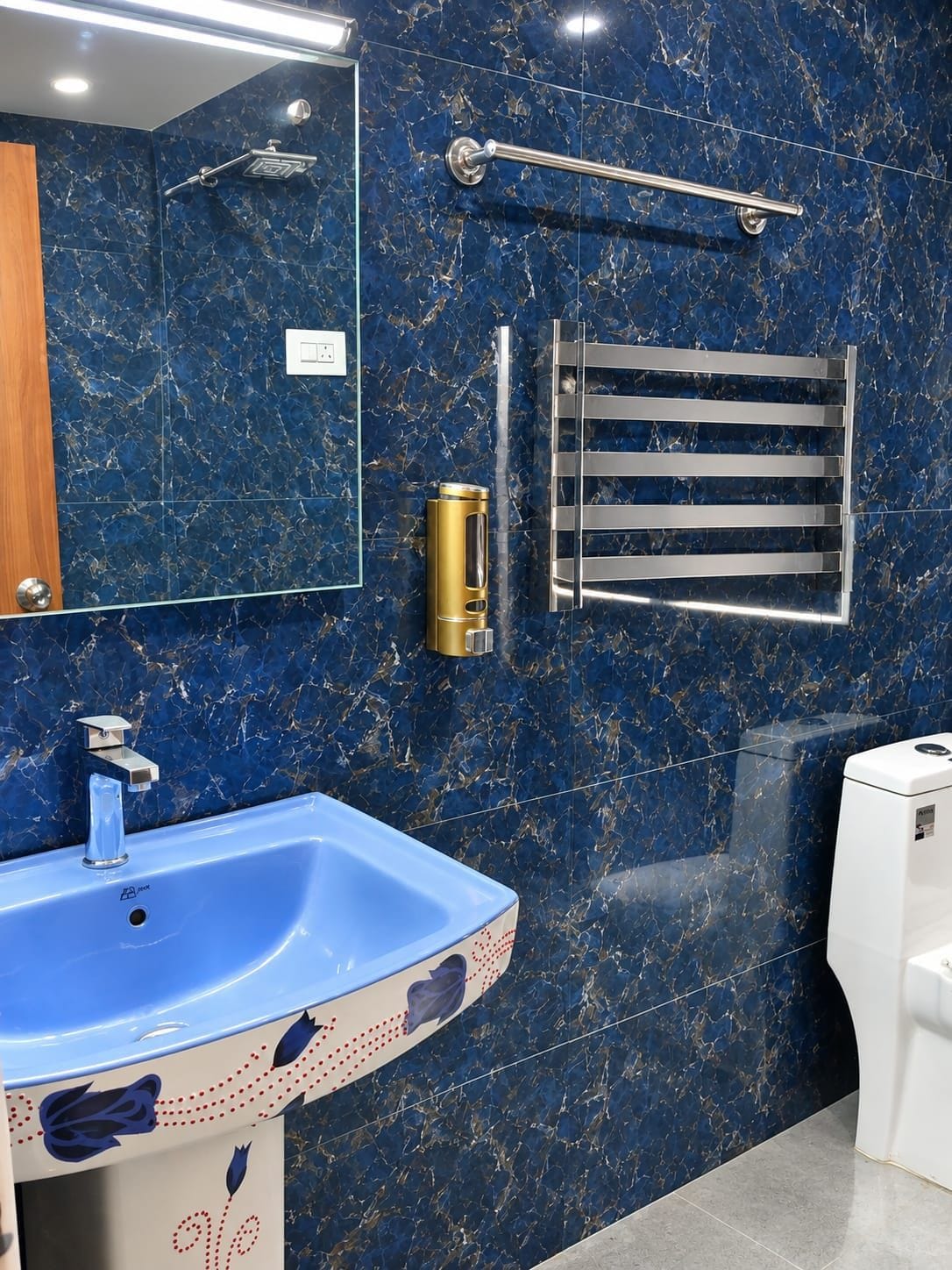 Un baño con un lavamanos de mármol azul, un cabezal de ducha manual, un perchero y un inodoro.