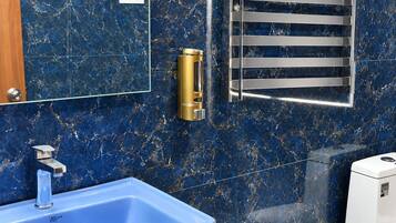 Un baño con un lavamanos de mármol azul, un cabezal de ducha manual, un perchero y un inodoro.