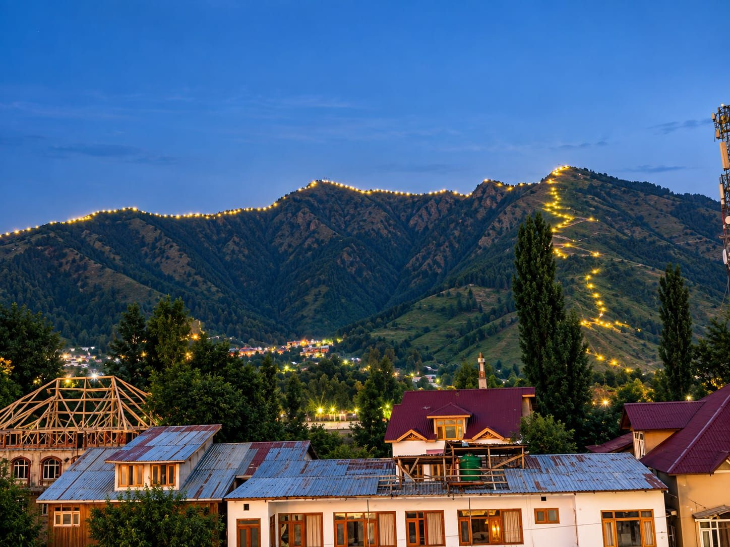 Un paisaje montañoso con un pueblo en la base, con casas tradicionales de techos metálicos y una estructura de madera destacada.