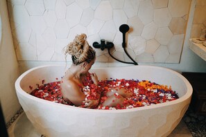 Eine Badewanne, gefüllt mit Wasser und Blütenblättern.
