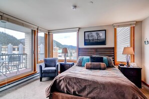Una camera d'albergo con un letto grande, due comodini, una sedia e vista sull'esterno.