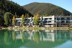 Un hotel sul lago con diversi edifici, vista chiara sul lago e una collina boscosa sullo sfondo.