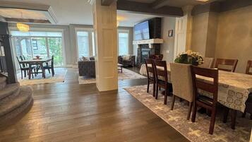 A spacious living area with a fireplace, a dining table, and a large TV screen.