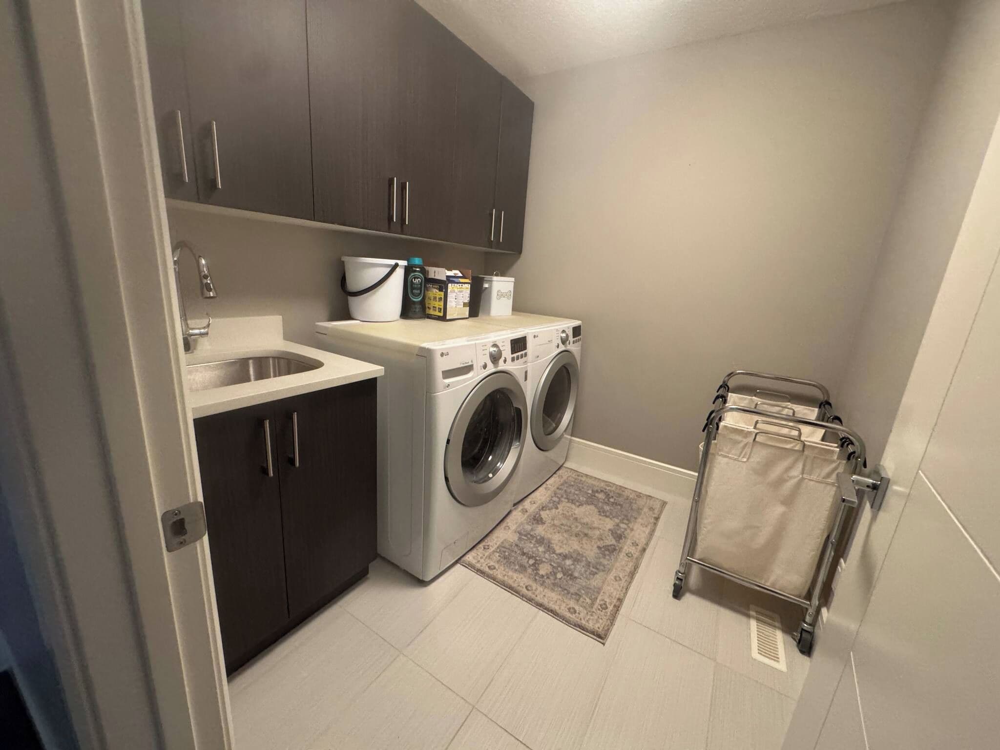 A laundry room with a washing machine, a sink, and cabinets.