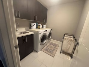 Een wasserette met een wasmachine, een wasbak en kastjes.