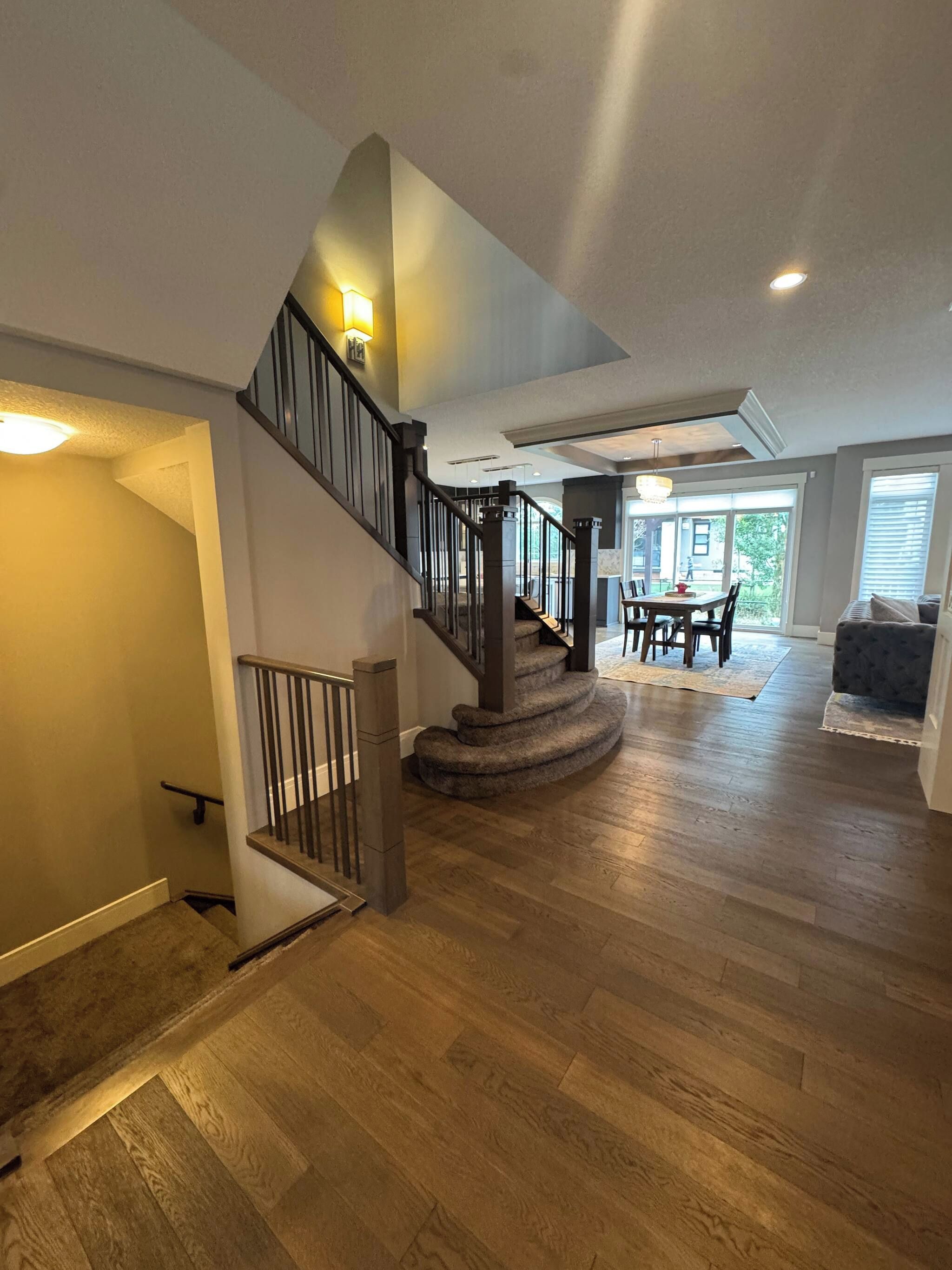 A spacious living area with a wooden staircase, a dining table, and a sofa.