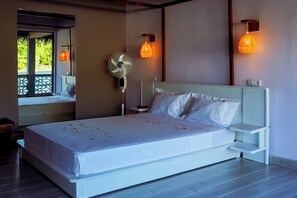 Un dormitorio con cama, mesitas de noche, un ventilador y lámparas de pared.