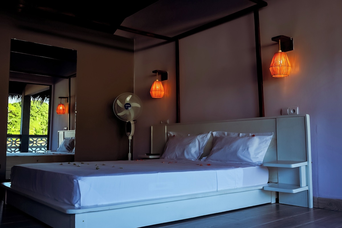 Un dormitorio con cama, un ventilador de pared y dos apliques.