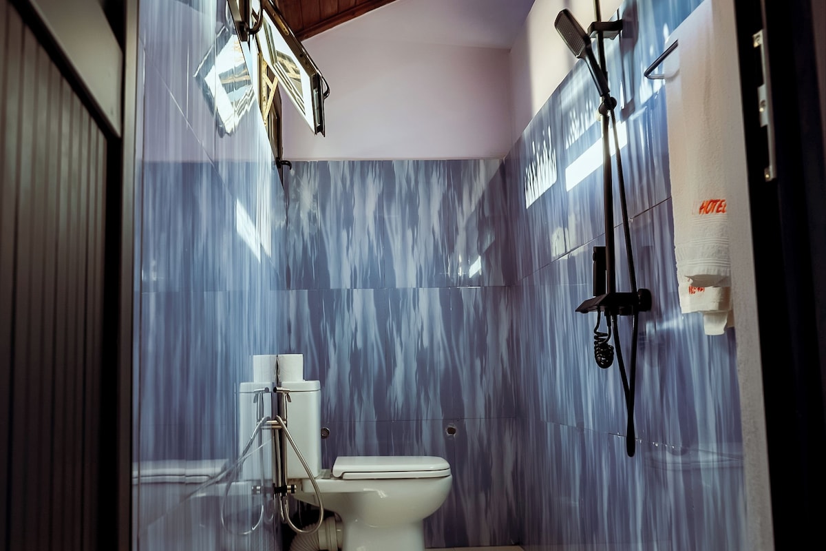 Un baño con inodoro, ducha y dispensador de toallas.