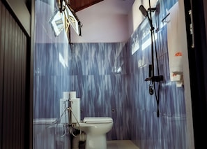 Un baño con inodoro, ducha y dispensador de toallas.