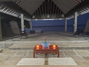 Eine überdachte Terrasse im Freien mit einem Tisch für zwei Personen, komplett mit Flasche und Gläsern, und zwei Stühlen mit Blick auf die Aussicht.
