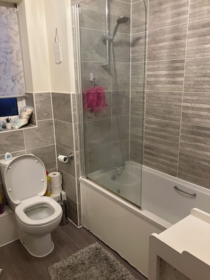 A bathroom with a glass-enclosed shower, a toilet, and a sink.