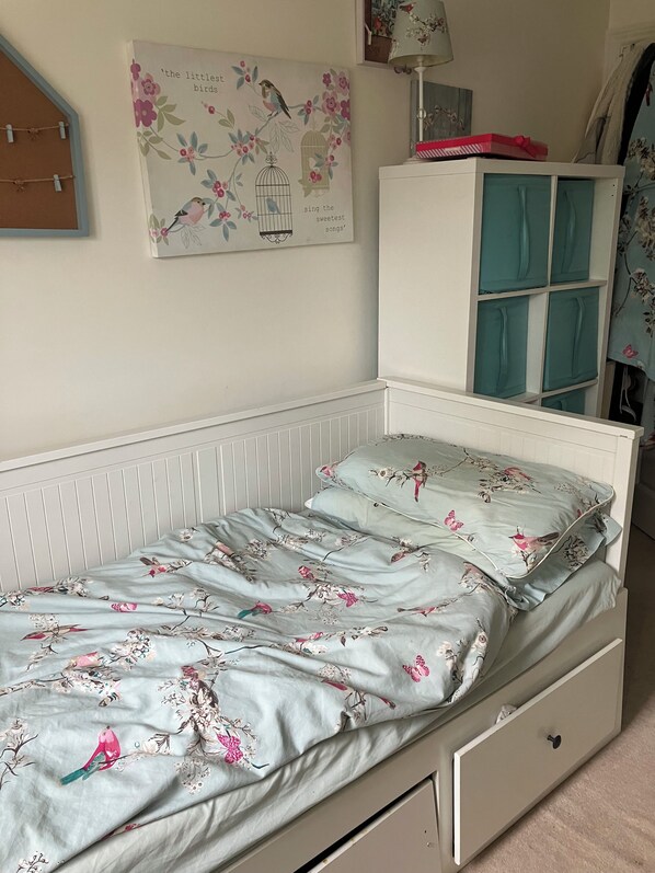A single bed with floral bedding, a white headboard, a wall-mounted picture, and a cabinet with teal doors. - Two rooms and one bathroom available for short term rental. Free parking! (Hemel Hempstead)