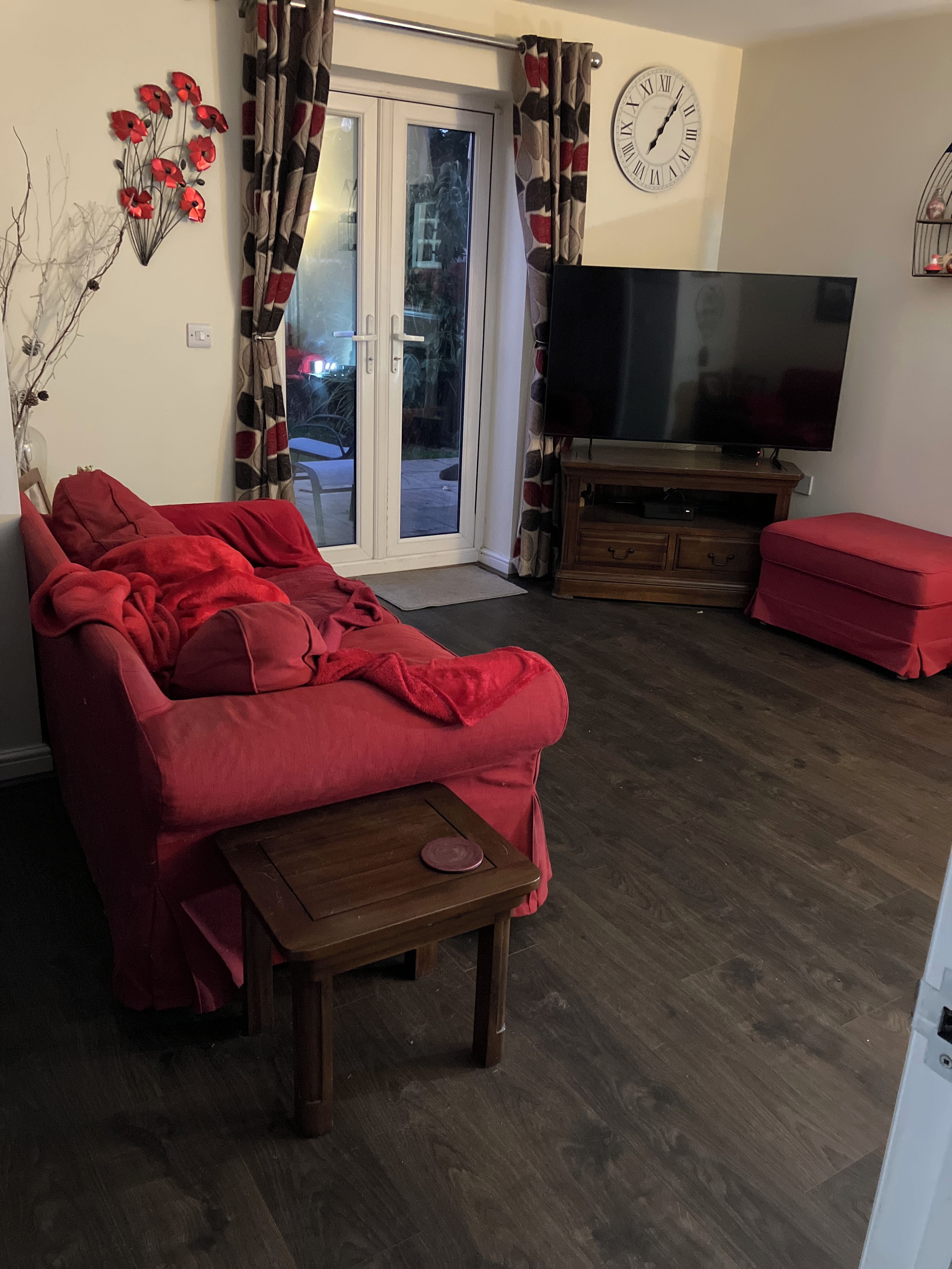 En stue med en sofa, et fjernsyn og et ur på væggen.