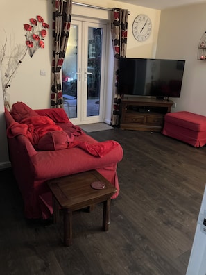 Ett vardagsrum med en soffa, en tv och en klocka på väggen.