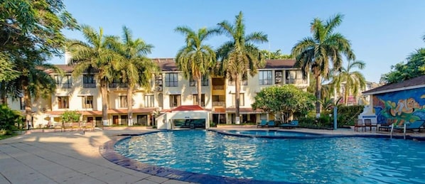 A hotel with a swimming pool, palm trees, and a mural on the building. - Otium Resort by the Oterra (Alto de Porvorim)