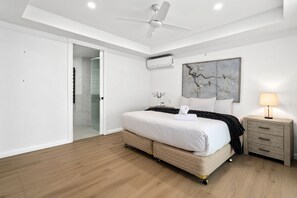 A bedroom with a bed, a nightstand, a lamp, a ceiling fan, and a wall-mounted air conditioner. - River Esplanade Penthouse (Mooloolaba)