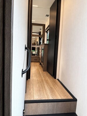 A hallway with a wooden floor and a black-framed door. - Cozy 1-bedroom mobile home in nice Keaau with AC (Keaau)